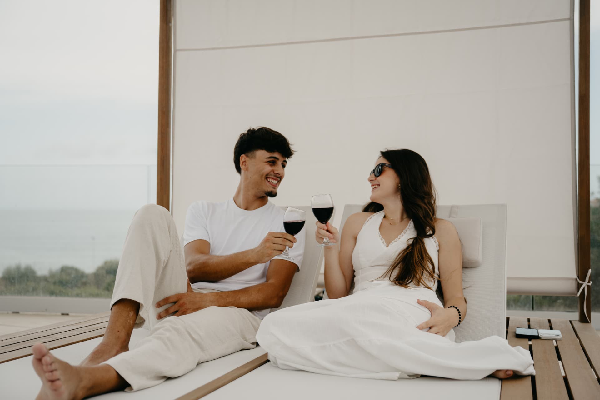 Pareja brindando en una cama balinesa con vistas al mar